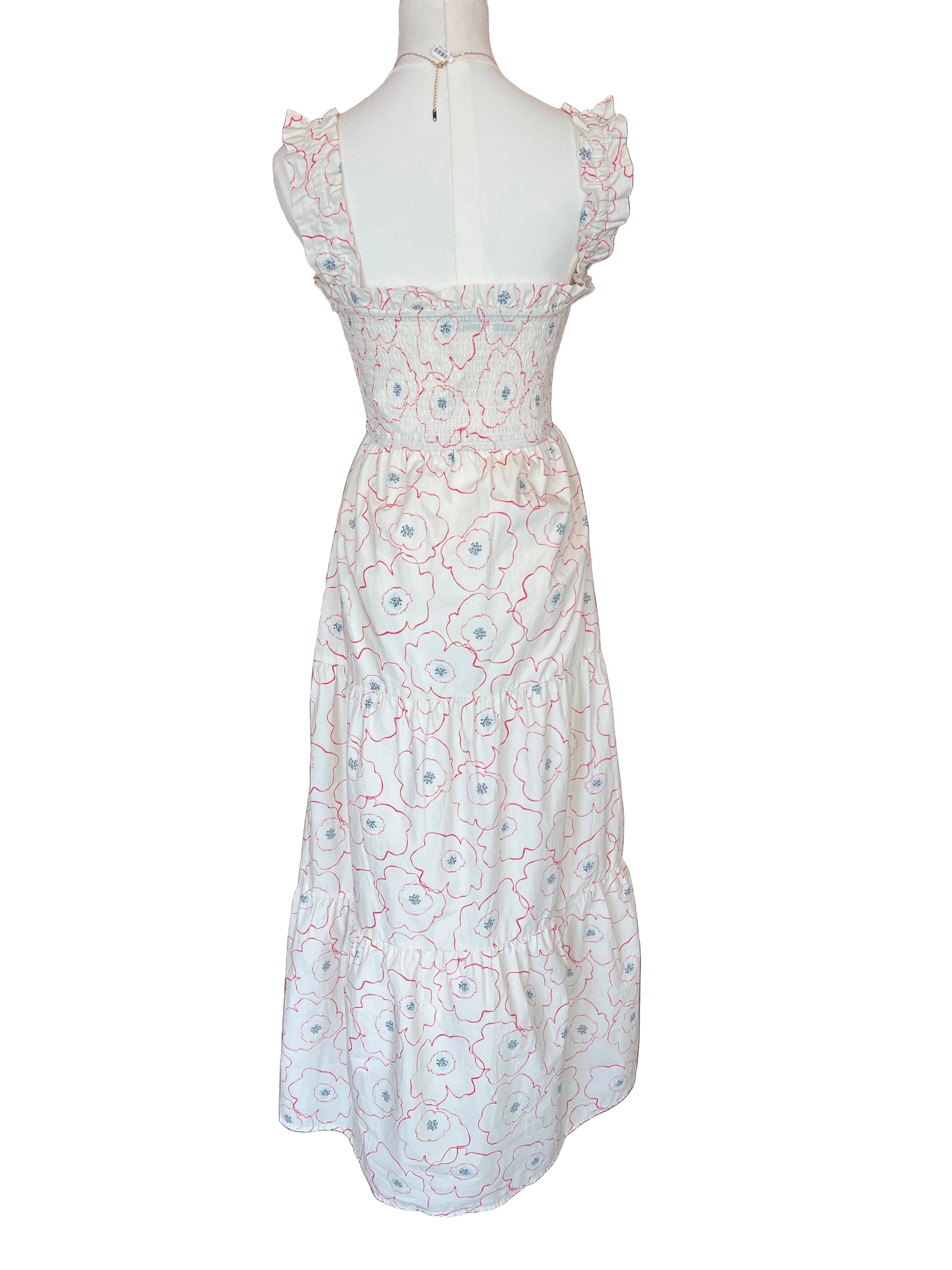Mannequin wearing a white dress with red floral patterns in a store setting